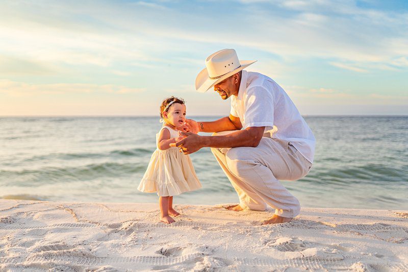 Dad wearing a cowboy had with his daughter at the beach in Alabama at a session with his photographer in Orange Beach, Al.