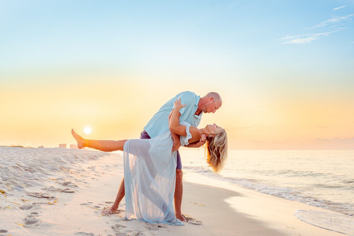 Take the Dip Photo of Couple taking a dip on the beach at sunset